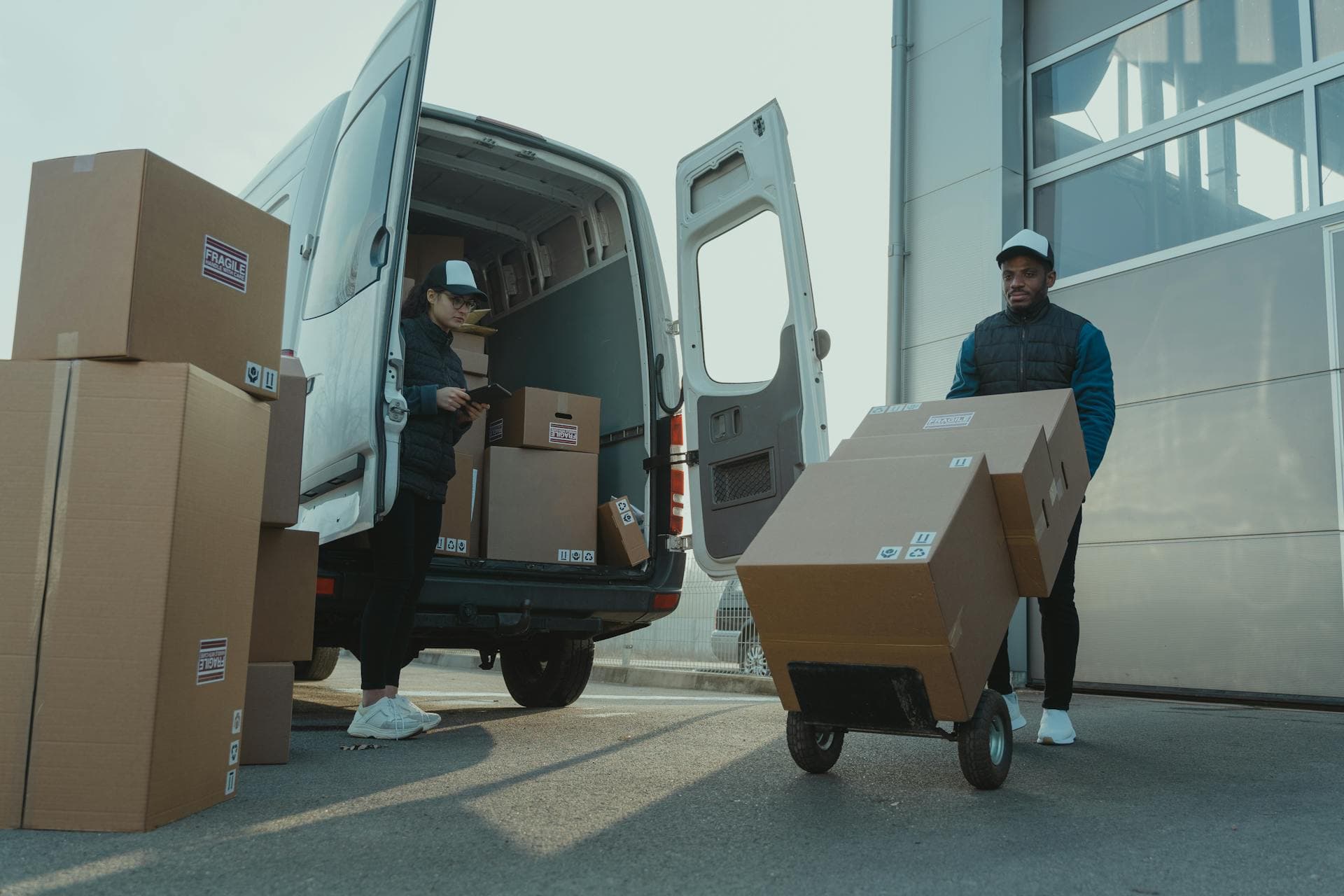 Two couriers loading parcel boxes from a delivery van